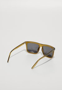 Ochelari de soare pătrați cu un cadru transparent de culoare chihlimbar și lentile de un gri închis. Temele sunt subțiri și ușor curbe. Fără logo-uri sau modele vizibile.