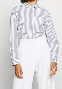 Gestreept overhemd in lichtgrijs en wit, met lange mouwen, een kraag, een enkele borstzak en contrasterende manchetstrepen.