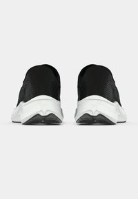 Ζεύγος μαύρα αθλητικά παπούτσια από δίχτυ με παχιά λευκά πέλματα, που φαίνονται από πίσω σε λευκό φόντο.