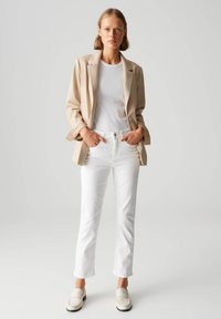 Beige blazer, witte nauwsluitende T-shirt, witte rechte jeans en lichte loafers. Soepele texturen, op maat gemaakt ontwerp en een neutraal kleurenpalet.