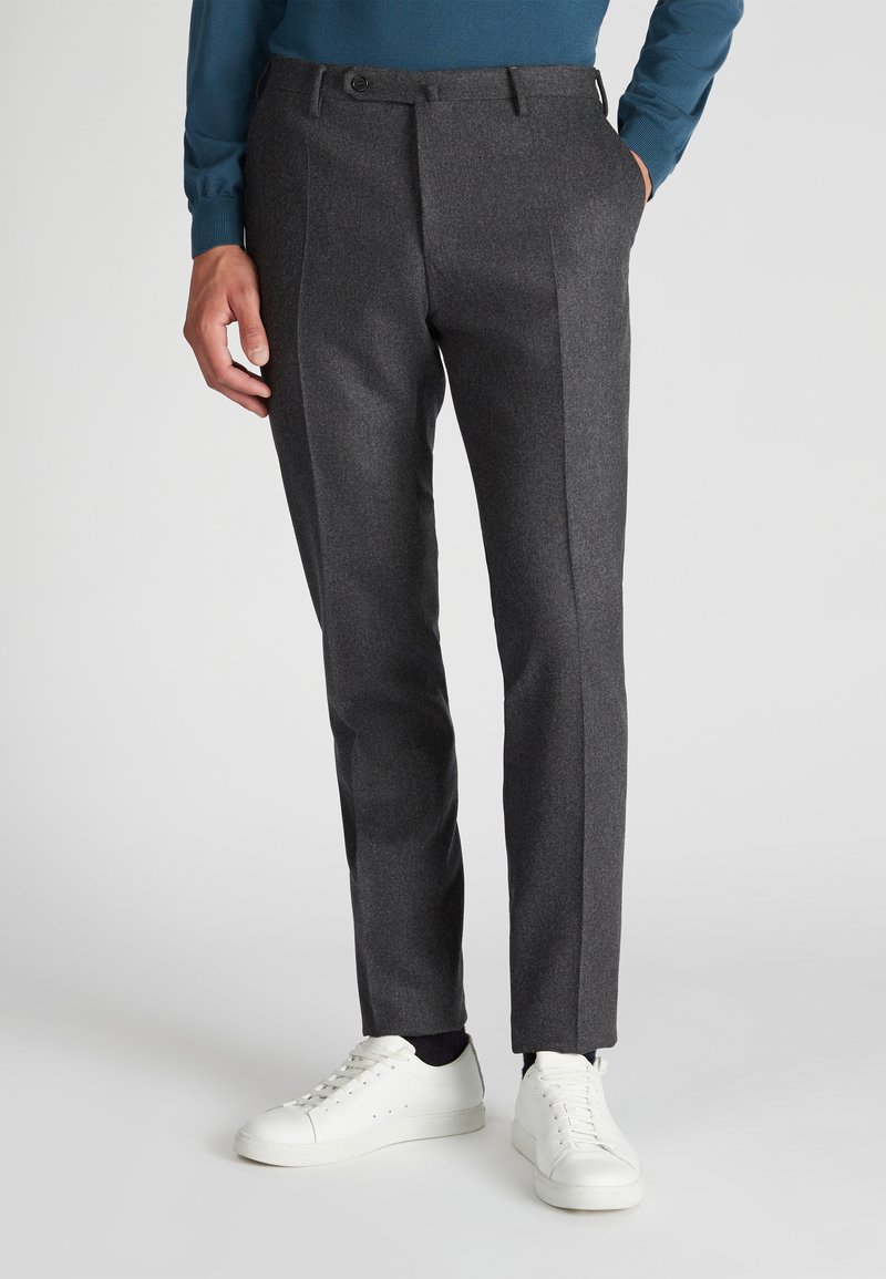 Graue maßgeschneiderte Hose aus strukturiertem Stoff mit Slim-Fit, versehen mit Vorderfalten und Seitentaschen, kombiniert mit weißen Sneakern.