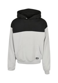 Le sweat à capuche présente un design bicolore avec une partie supérieure noire et une partie inférieure gris clair, une poche kangourou et des poignets côtelés.