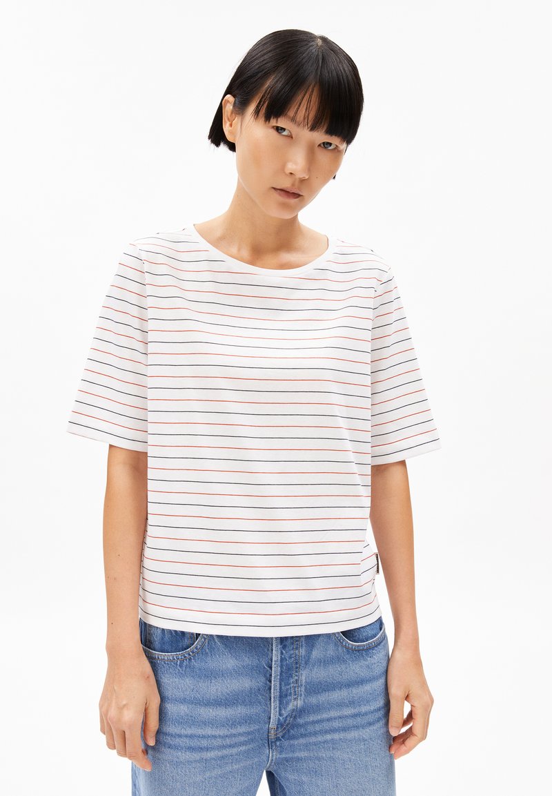 White short-sleeve T-shirt featuring thin red horizontal stripes, round neckline, and a relaxed fit. Paired with light blue denim jeans.