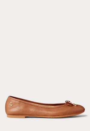 Καφέ δερμάτινο μπαλαρίνα με μικρό φιόγκο και χρυσή λεπτομέρεια λογοτύπου στη φτέρνα και στις άκρες του φιόγκου πάνω σε απλό φόντο.