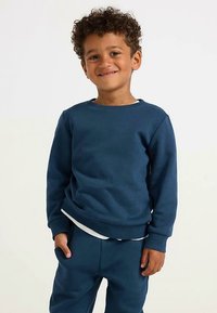 Navy blue sweatshirt features a round neck, ribbed cuffs, and a relaxed fit. Paired with matching pants in the same fabric and color.