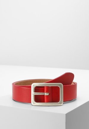 Opgerolde rode leren riem met een grote zilveren rechthoekige gesp, rustend op een witte ondergrond.