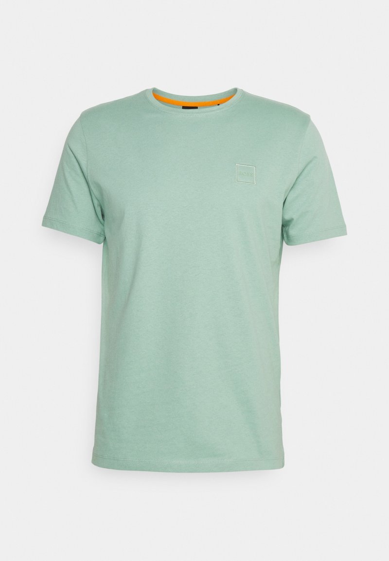 T-shirt vert clair à manches courtes avec col rond, petit logo en relief sur le côté gauche de la poitrine et bordure orange à l'intérieur du col.
