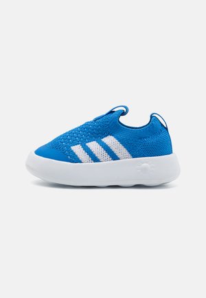 Blue knitted sneaker with white three-stripe design, slip-on style, and cushioned white rubber sole. Features textured upper and pull tab.