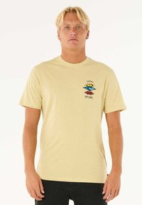 Korte mouwen, lichtgele katoenen t-shirt met een kleurrijk grafisch logo op de linkerborst en een standaard pasvorm.