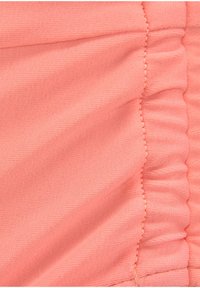 Korallenfarbene Stoff mit einer weichen, strukturierten Oberfläche. Zeigt versammelte Details am Rand, dargestellt in einer Nahaufnahme.