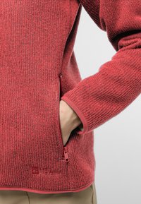 Rote strukturierten Fleece-Jacke mit einer Reißverschlusstasche und elastischen Bündchen. Verfügt über ein glattes Futter und ein körpernahes Design.