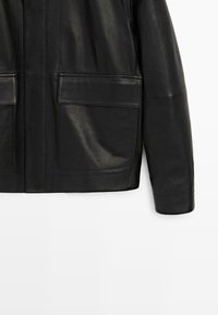 Sort læderjakke med en glat tekstur, der har to store forlommer og et strømlinet, moderne design.