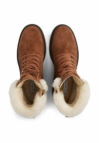 Botas de tobillo de ante marrón con forro de piel sintética color beige, punta redonda, ojales dorados y cordones. Diseñadas para brindar calidez y confort.