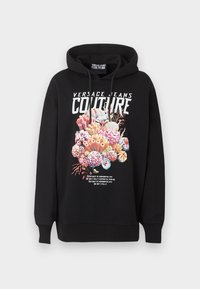 Sudadera negra con capucha con texto "Versace Jeans Couture", gráfico colorido de arrecife de coral y texto pequeño impreso debajo del gráfico en la parte frontal.