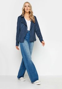 Marinblå faux läder bikerjacka med dragkedja framtill, breda kragar och långa ärmar, tillsammans med högmidjade ljusblå denimflarejeans.