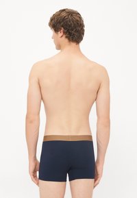 Herren Boxershorts in Marineblau mit einem glatten braunen Bund. Der Stoff wirkt weich und dehnbar, ausgelegt für Komfort und Passform.