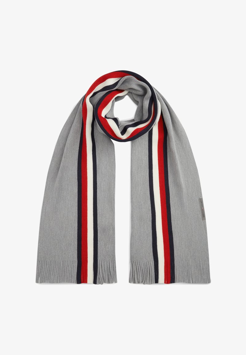 Écharpe tricotée gris clair avec des rayures verticales rouges, blanches et bleu marine et des franges courtes aux deux extrémités, posée à plat avec une boucle en haut.