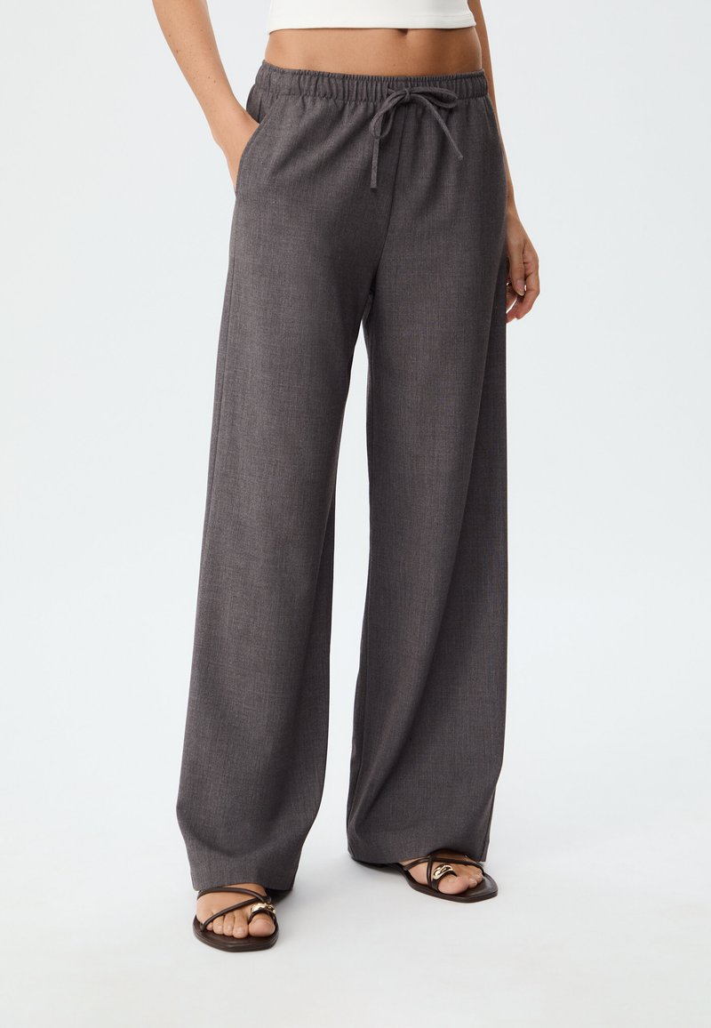 Wide-leg charcoal grey pants made of textured fabric, featuring an elastic waistband with a drawstring and side pockets.