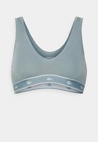 Šviesiai mėlynas sportinis liemenukas su suapvalintu kaklu, pagamintas iš minkštos medžiagos. Savybės - kontrastinga juosta su pakartotu Lacoste logotipu.
