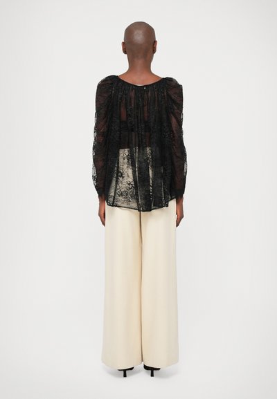 Must mustriba mustrega, millede õhkavad varrukad, poolläbipaistev kangas, koos kõrge vöökohaga laia jalamise kreemikate pükstega.