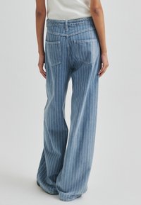 Világoskék csíkos farmernadrág magas derékkal, széles szárakkal és két hátsó zsebbel. Az anyag puha tapintású és hétköznapi dizájnnal rendelkezik.