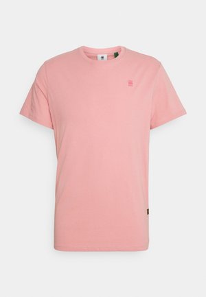 T-shirt rose clair à manches courtes et col rond, avec un petit logo sur la partie supérieure gauche de la poitrine et une étiquette en tissu près de l'ourlet inférieur.