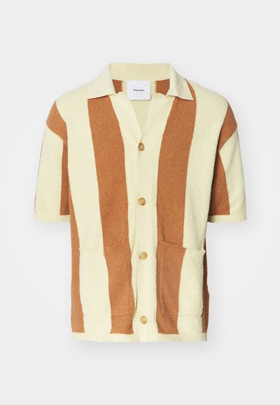 Cardigan a maniche corte in crema e marrone a righe, con chiusura a bottoni, due tasche anteriori e un materiale morbido e peloso.