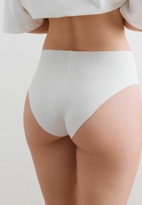 Culotte blanche haute sans couture fabriquée à partir d'un tissu doux, présentant une texture lisse et des coutures minimales pour un confort optimal et une silhouette épurée.