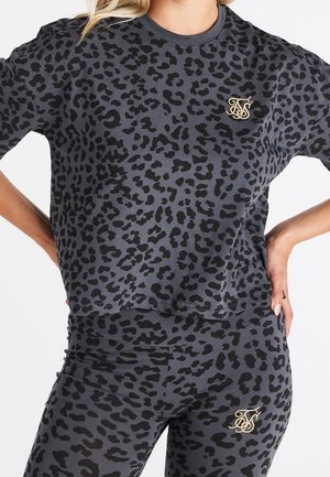 Felpa grigia con stampa maculata, maniche corte, presenta un motivo nero e un dettaglio logo dorato sul petto. Abbinata a leggings coordinati.