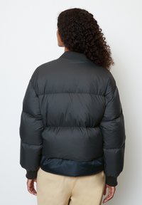 Black puffer jacket with a quilted pattern, ribbed cuffs, and a high neckline, featuring a smooth exterior and a cropped silhouette.