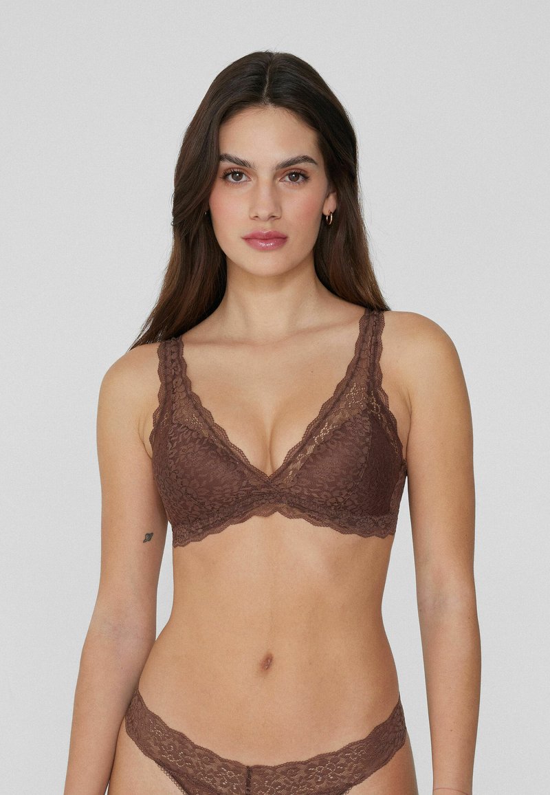 Krajkový bralette v tmavě hnědé barvě se zvlněnými okraji, trojúhelníkovým tvarem a širokými ramínky. Měkký materiál s jemným vzorem.