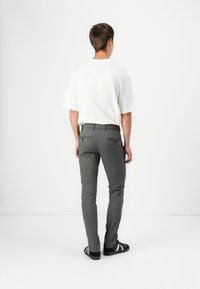 Grau maßgeschneiderte Hosen aus einem strukturierten Stoff, mit passgenauem Schnitt, Gesäßtaschen mit Reißverschlüssen und einem braunen Lederbund.