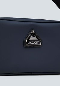 Borsa rettangolare blu scuro realizzata in materiale liscio, con una patch a logo triangolare nera e hardware color argento.