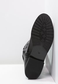 Bottines noires avec une semelle en caoutchouc texturé, fermeture éclair sur le côté, et tige en cuir lisse. Taille 36 marquée sur la semelle.