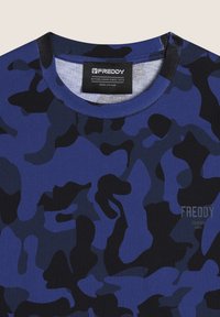 T-shirt blu camouflage con collo rotondo, maniche corte e una texture morbida. Presenta un'etichetta nera "FREDDY" all'interno del collo.