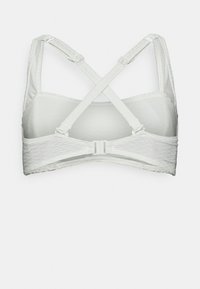 Sutiã desportivo branco com uma banda texturizada, alças cruzadas ajustáveis e um fecho de gancho nas costas. Tecido liso com bordas sem costura.