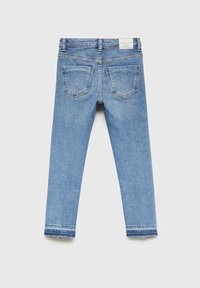 Svetlo modri jeans z ožjim krojem. Zadnji žepi z ukrivljenimi šivi, raztrgan rob in oznaka v bližini pasu.