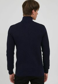 Maglione lavorato a maglia blu navy con colletto alto, caratterizzato da un motivo a zigzag testurizzato, polsini a coste e orlo.