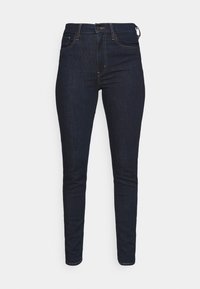 Jeans skinny de denim en azul oscuro, con cintura alta, cinco bolsillos y costuras en contraste para un aspecto elegante y ajustado.