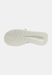 Semelle de chaussure en caoutchouc blanc avec un motif de semelle ondulée, dotée d'une finition lisse et d'une légère courbure au niveau du talon pour un soutien ergonomique.
