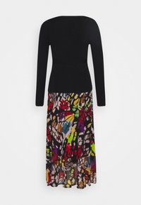 Corsage en maille noire à manches longues, associé à une jupe en mousseline florale multicolore arborant des motifs audacieux et abstraits ainsi qu'un design fluide.