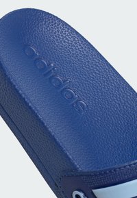 Chinelo azul com superfície texturizada. Apresenta um logótipo em relevo e uma tira contrastante. Sola interior suave e material durável.