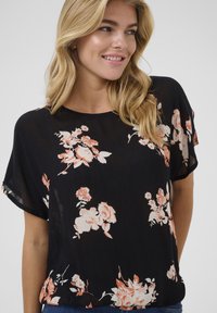Black floral blouse made of lightweight fabric, featuring peach and white floral patterns, short sleeves, and a relaxed fit.