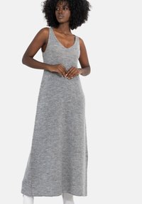Szara dzianinowa maxi sukienka z głębokim dekoltem w kształcie litery V, bez rękawów i miękką teksturą. Ma prostą sylwetkę sięgającą kostek.