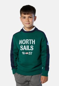 Sudadera verde con mangas en navy, que presenta un logotipo impreso en blanco "NORTH SAILS" y el año "1957". Puños y dobladillo acanalados. Textura suave.
