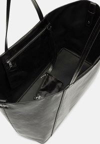 Czarna skórzana torba tote o gładkiej teksturze, z dwoma wnętrzami, z czego jedno z suwakiem. Otwarte wnętrze, solidne uchwyty i przestronny środek.