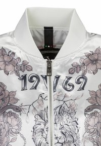 Vit bomberjacka med blommiga och lejongrafik, silverdragkedja, ribbad krage och intrikata svarta och rosa detaljer.