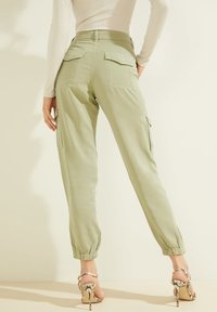 Vaaleanvihreät cargo-housut, joissa on elastiset hihnat; varustettu kahdella takataskulla ja sivutaskuilla. Käärmeennahkakuosiset korkokengät täydentävät asua.