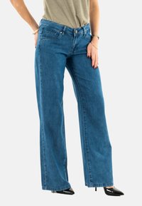 Vaqueros de pierna ancha en denim azul, con un diseño de bolsillo frontal, cierre de botón y silueta recta. Textura suave con un mínimo de detalles.