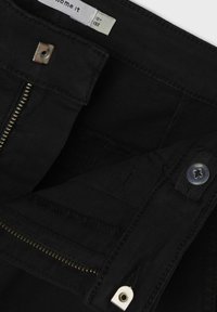Zwarte broek met ritssluiting, metalen knoop en meerdere zakken; kenmerkt zich door een textuurstof en een recht gesneden ontwerp.